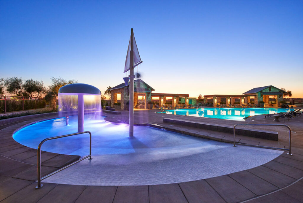 The Lodge at Riverstone has a gorgeous pool with lounge seating, shaded patio areas, and a kid-friendly splash pool (pictured here at night.)